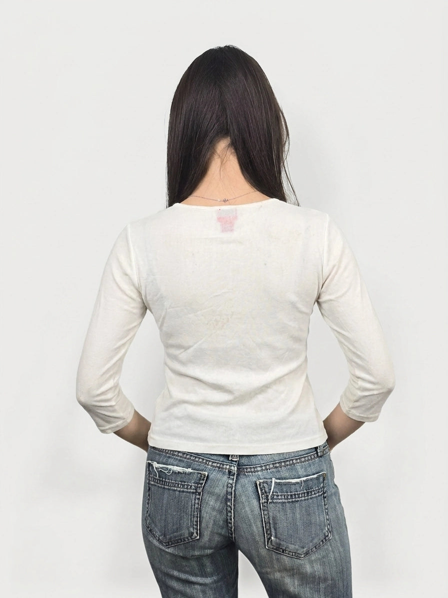 Back view of a white long sleeve top with embellishments.