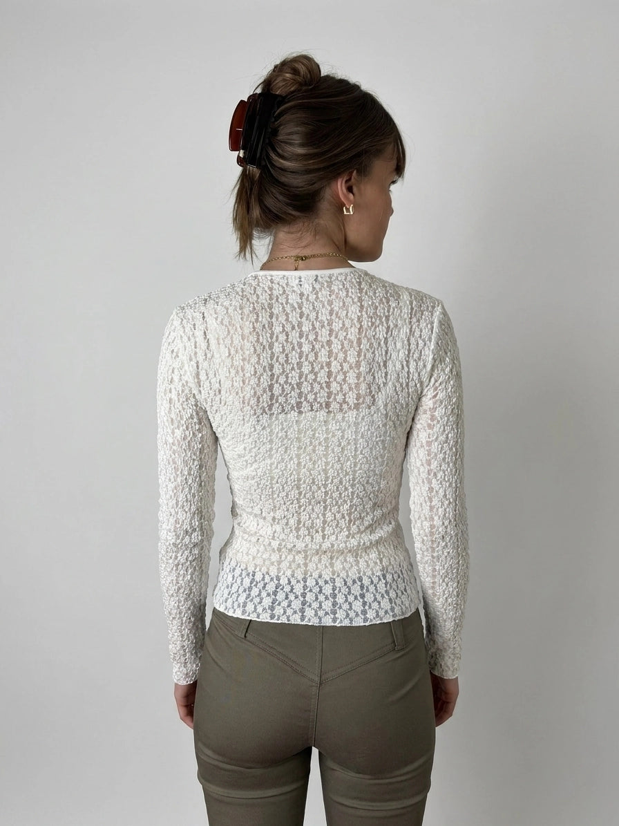 Back view of a white sheer long sleeve blouse with textured pattern.