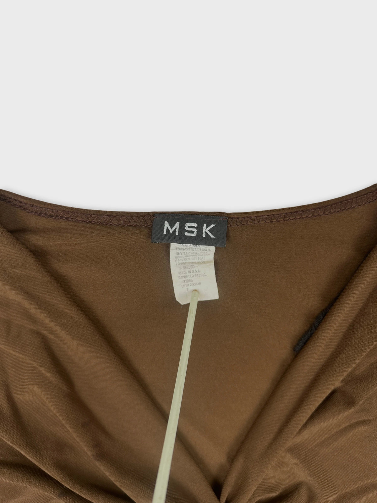Detail view of a brown women body shirt with a tag visible