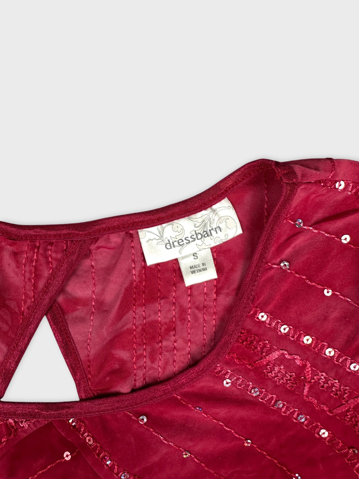 Detail view of burgundy body shirt with sequined pattern and textured stitching.