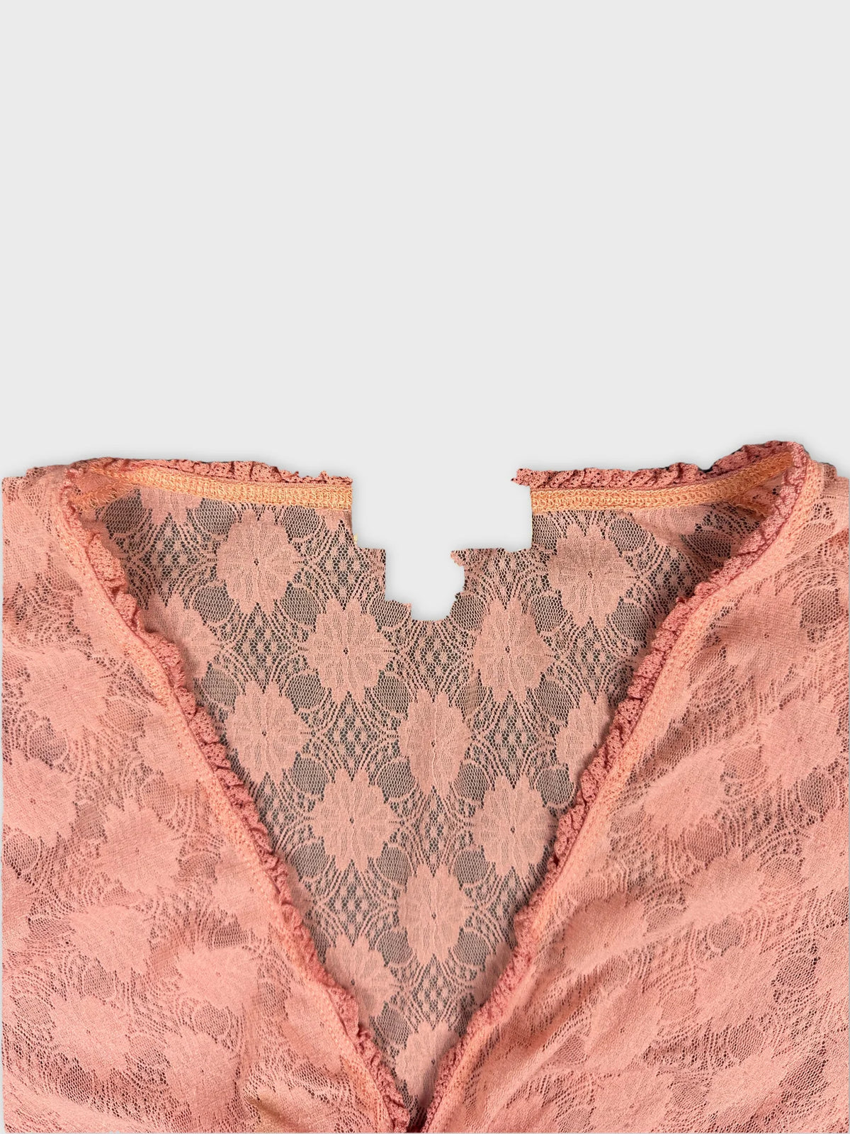 Detail view of a women's body shirt in blush pink lace with scalloped trim.