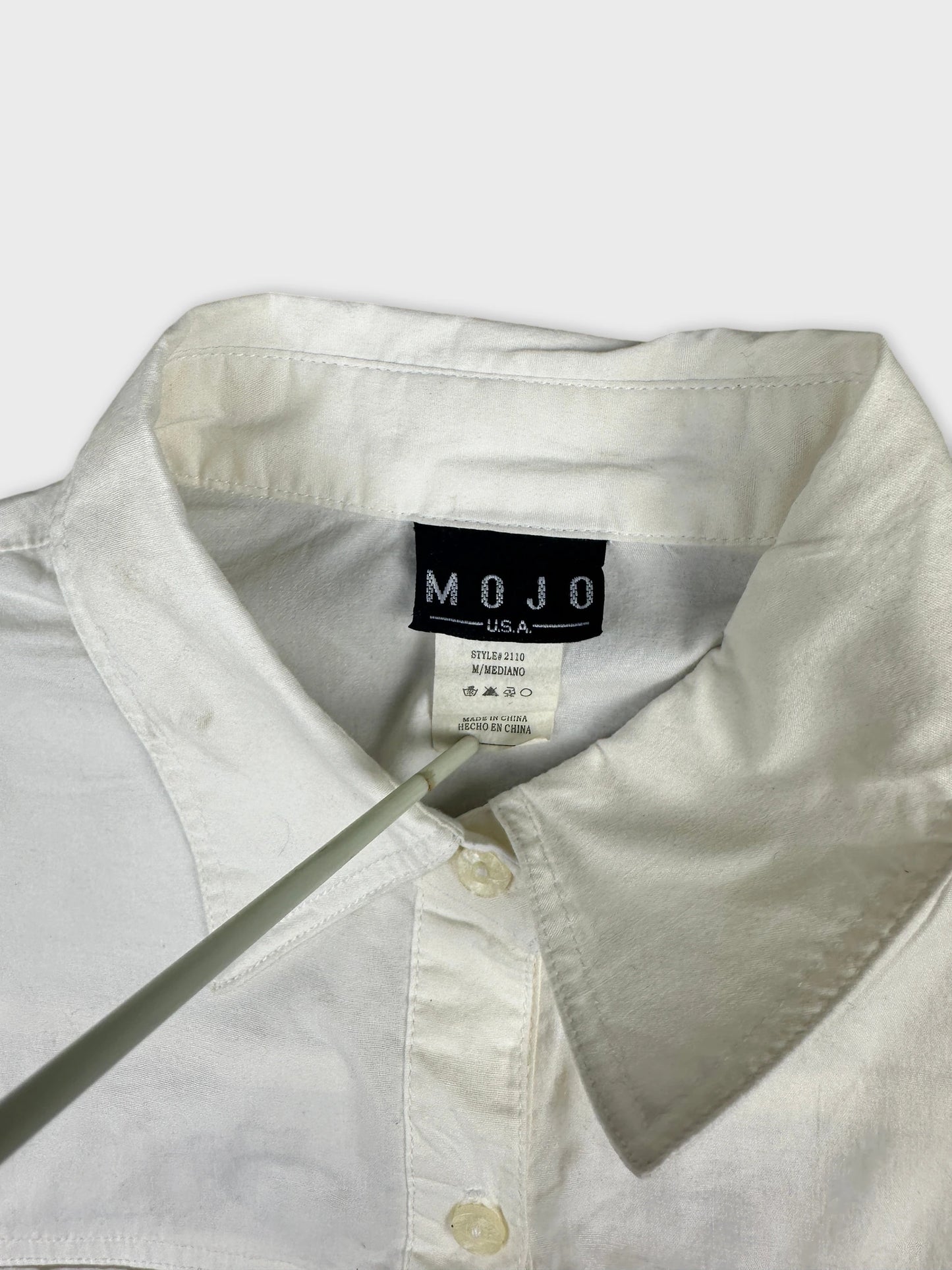 Detail view of a white women body shirt with a classic collar and button closure.