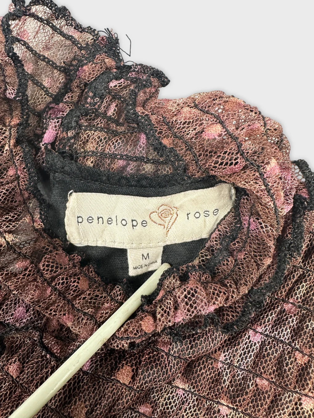 Detail view of a woman body shirt in dark pink with lace trim.