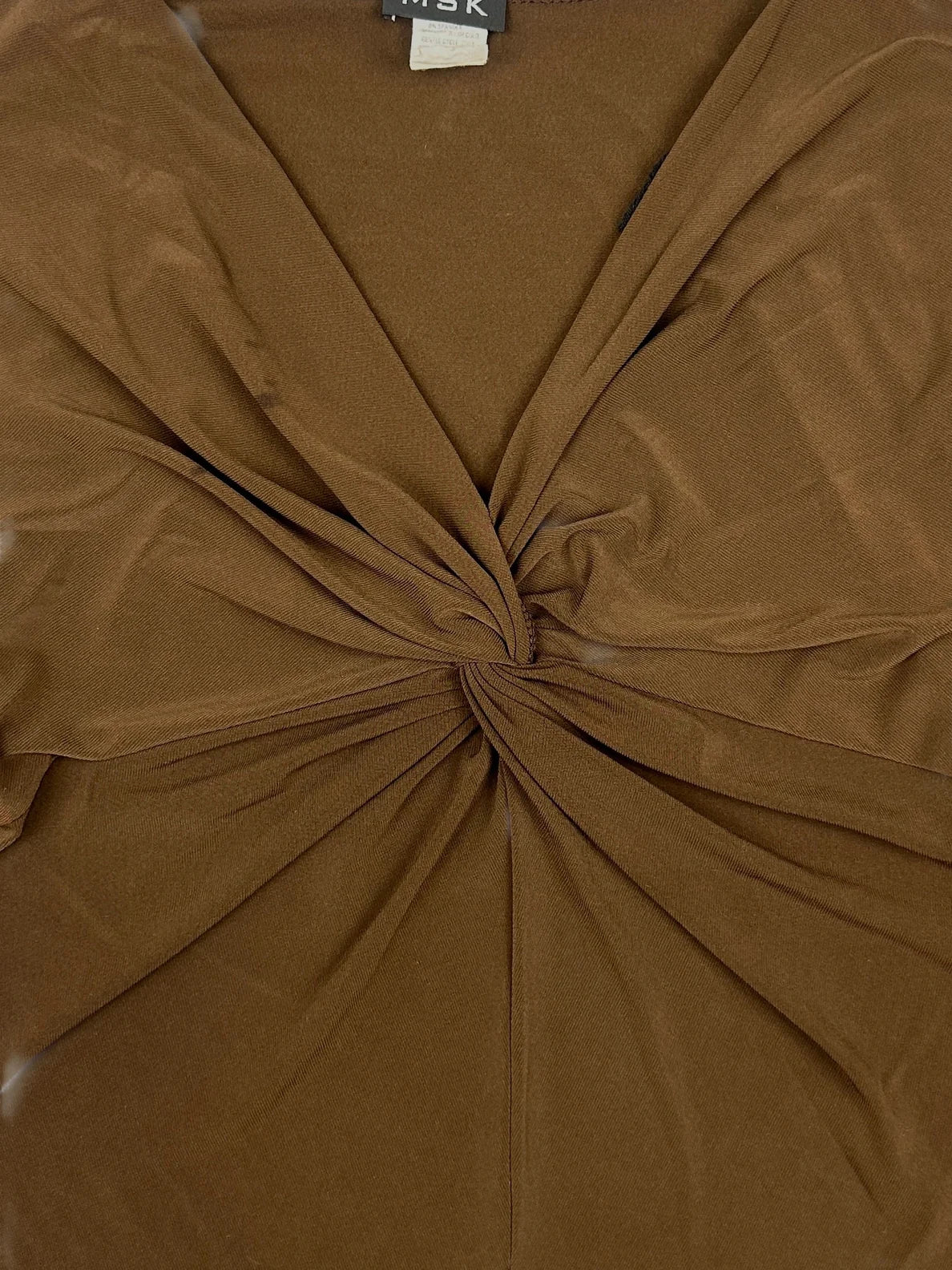 Detail view of a brown women body shirt featuring a twisted front design.