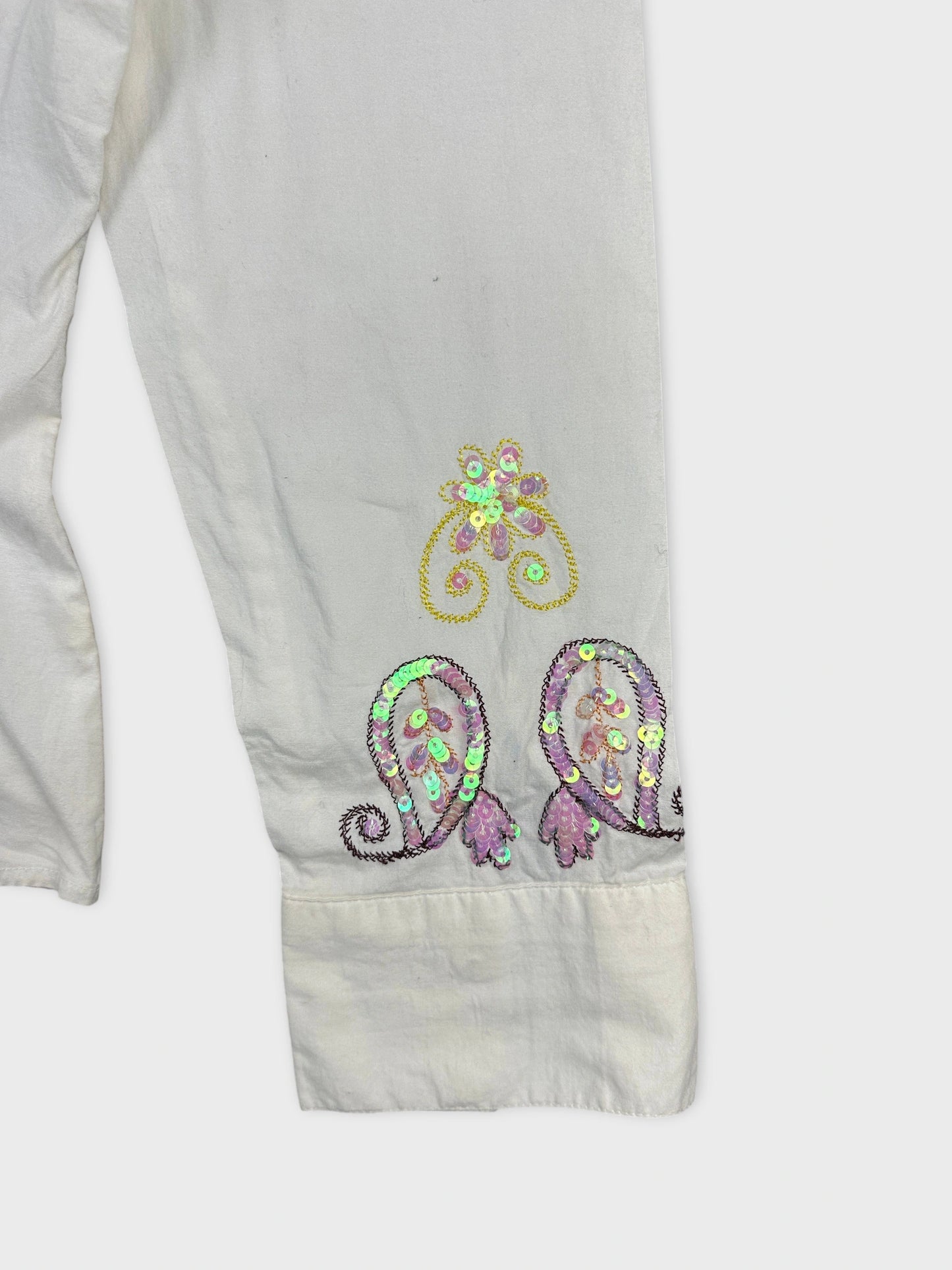 Detail view of a vintage body shirt featuring sequined floral patterns in pastel colors.