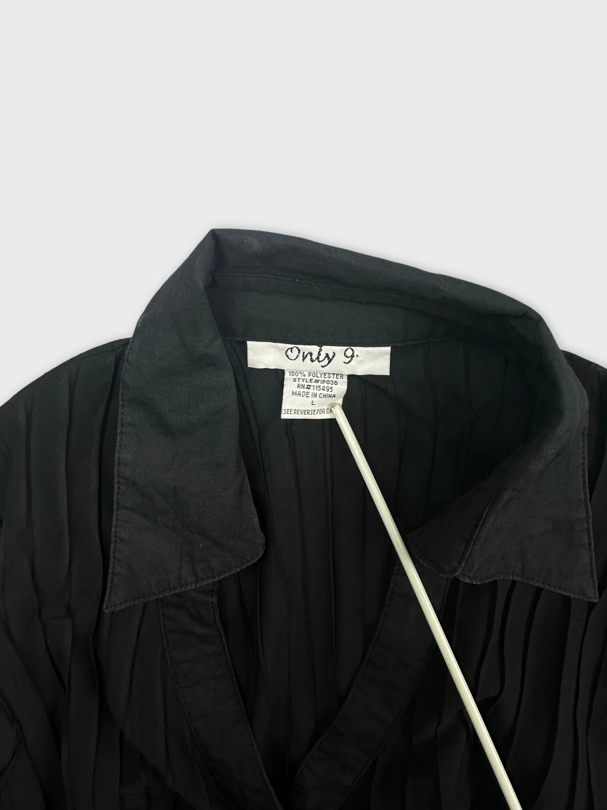 Detail view of a black women's body shirt with pleated texture.
