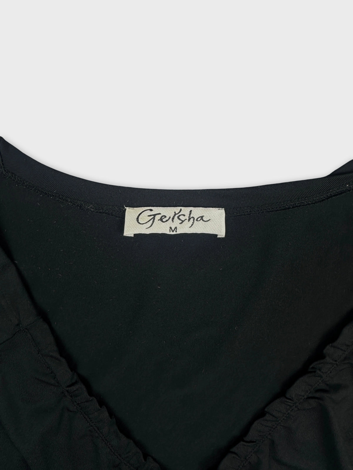 Detail view of a black women’s body shirt with gathered neckline.