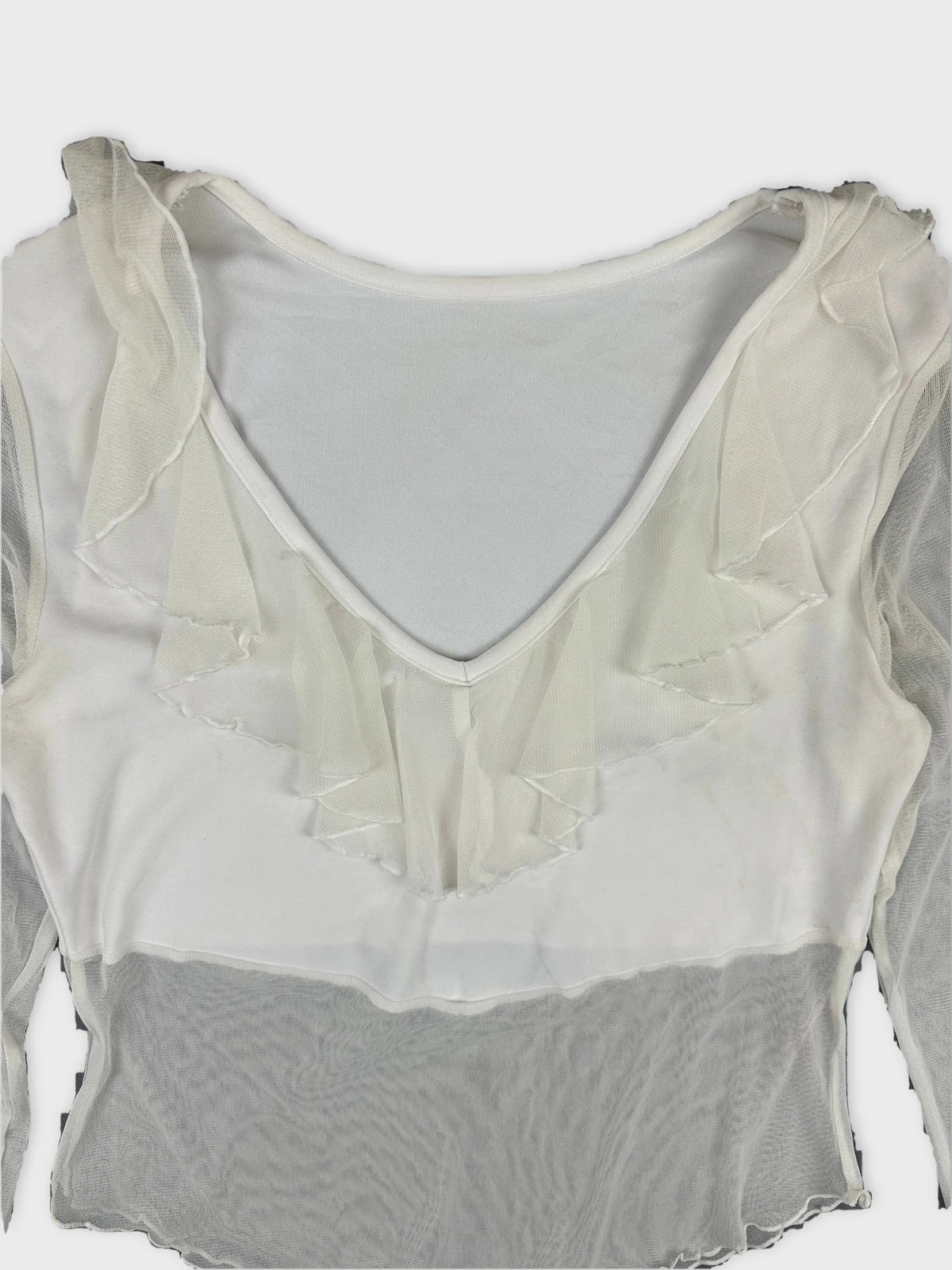 Detail view of a white body shirt featuring ruffled trim