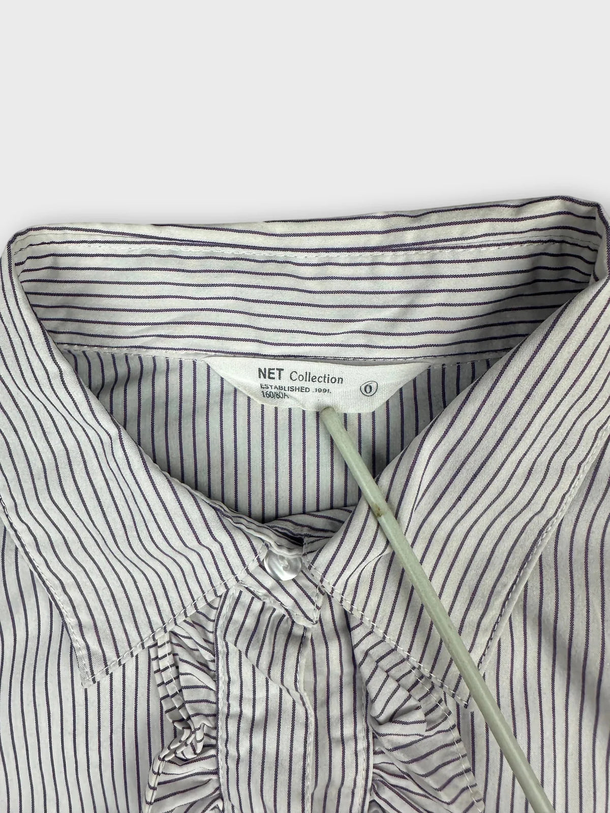 Detail view of a women’s body shirt in white with purple stripes.