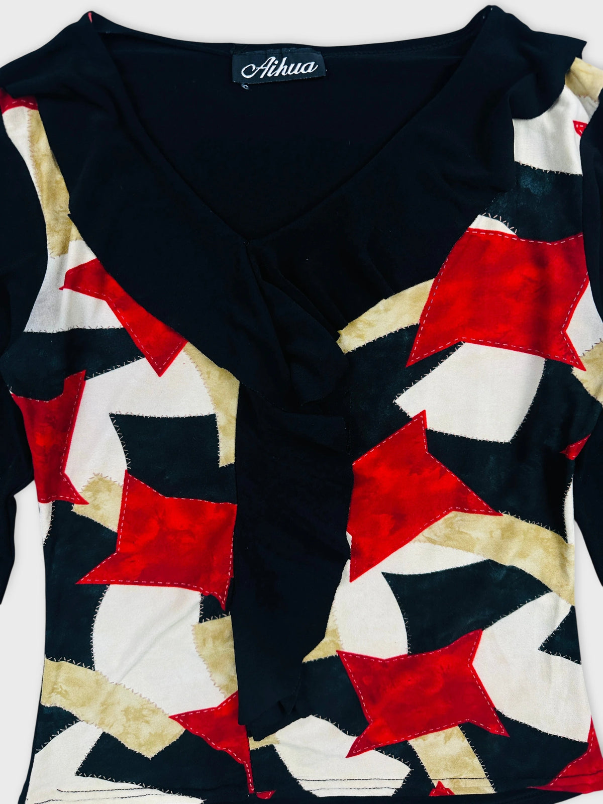 Detail view of a vintage black and patterned body shirt featuring star shapes.