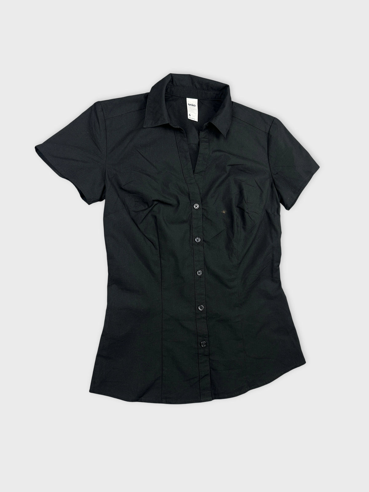 Detail view of a black women’s body shirt featuring a button-up design.