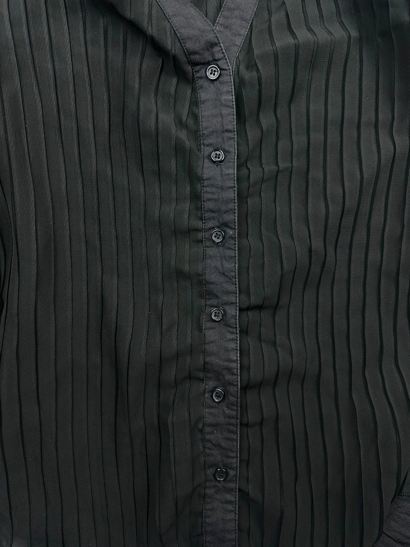 Black body shirt detail view featuring vertical ribbed texture and button closure.