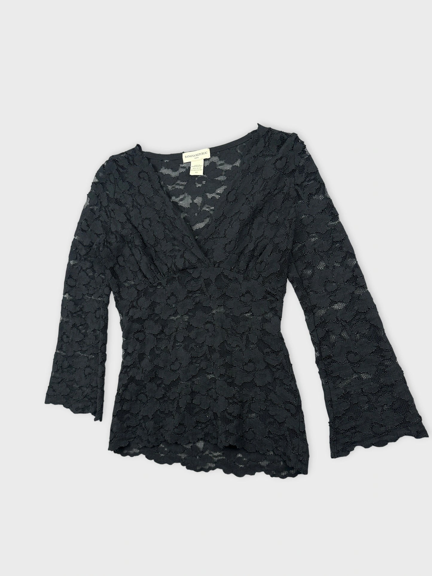 Detail view of a black lace body shirt with bell sleeves.