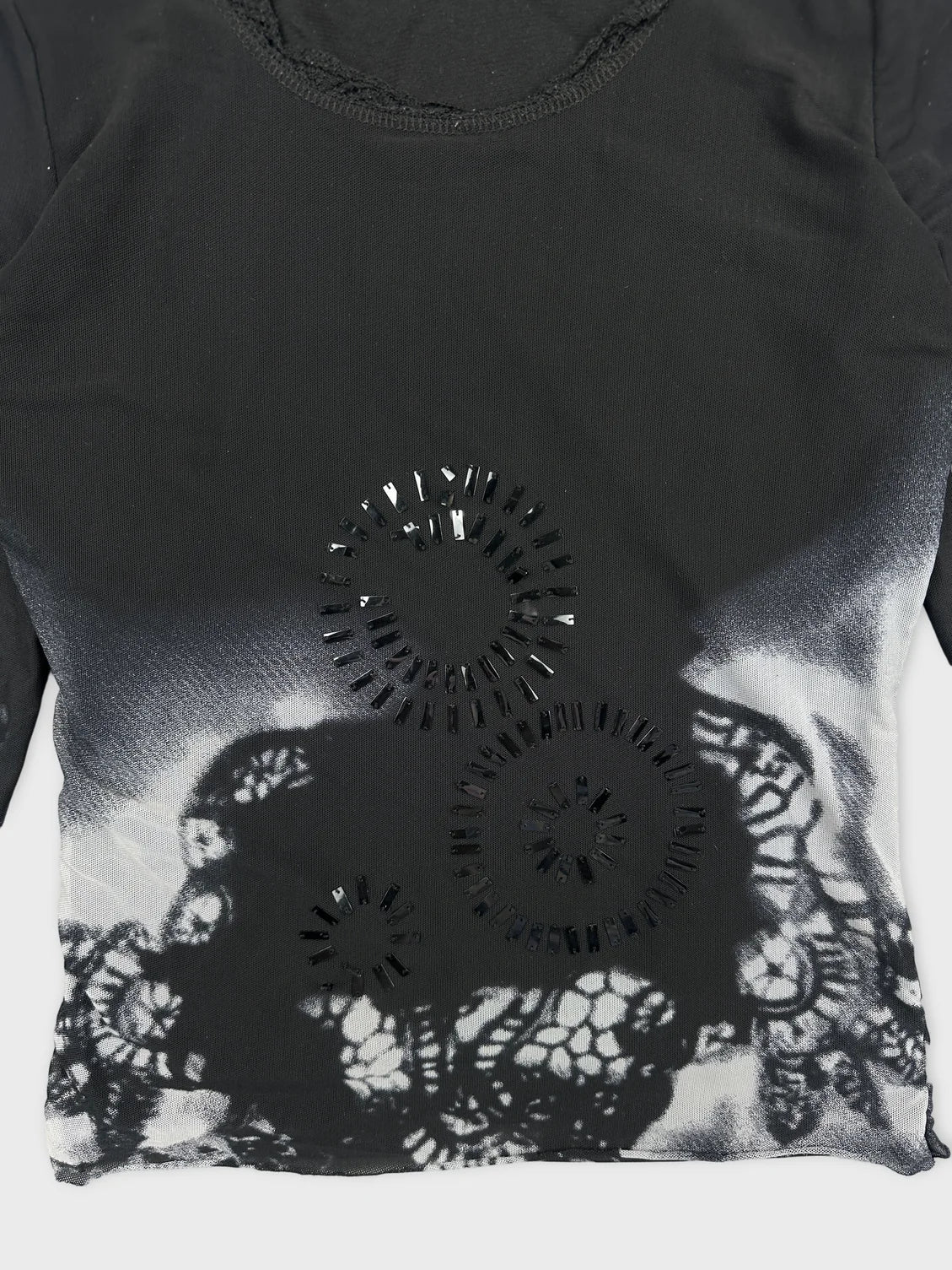 Detail view of a black body shirt with lace and cut-out pattern.