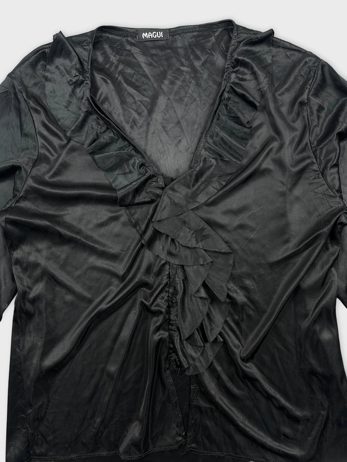 Detail view of a black women body shirt featuring ruffled trim.
