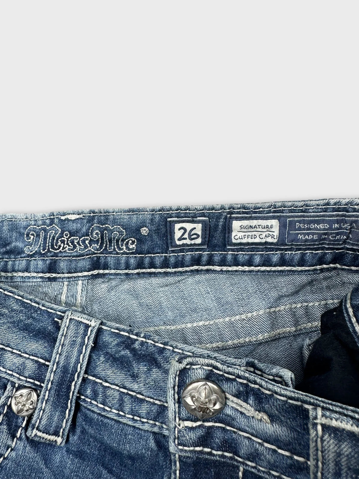 Detail view of blue denim body shorts with decorative silver buttons