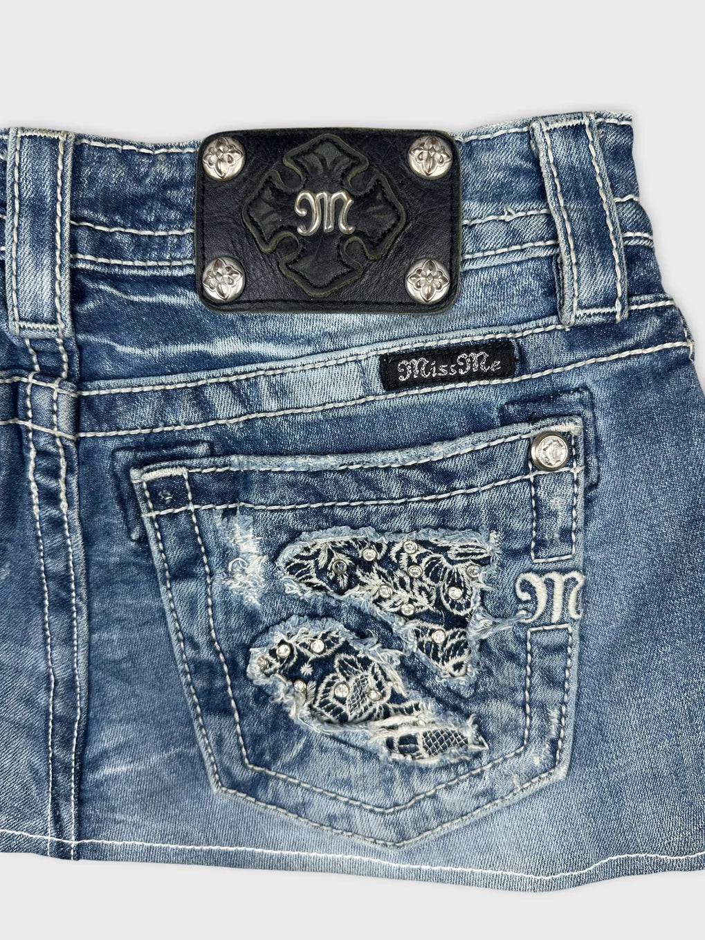 Detail view of blue denim body shorts with embroidered pockets.
