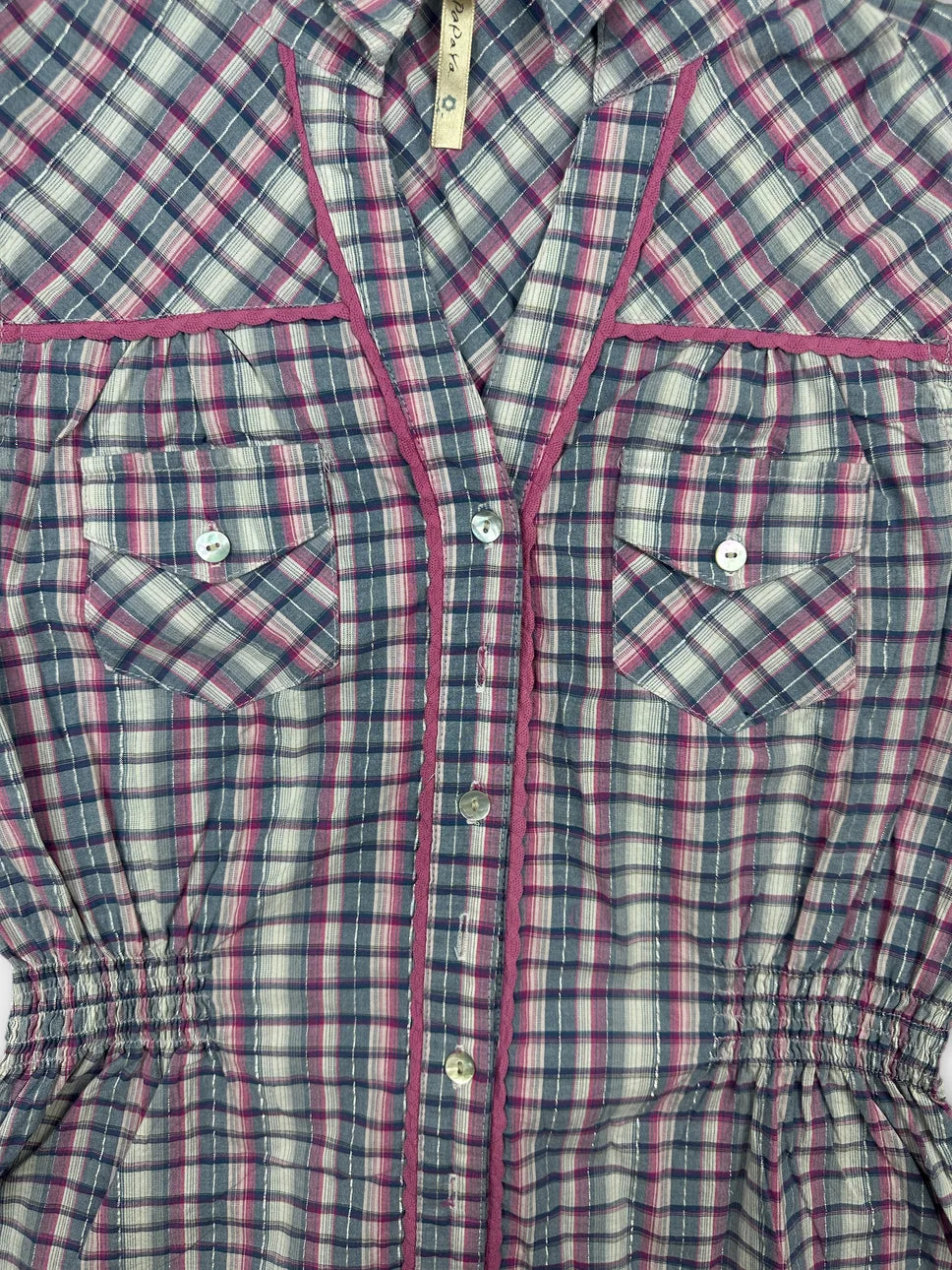 Detail view of a plaid button-up shirt in navy with pink trim.