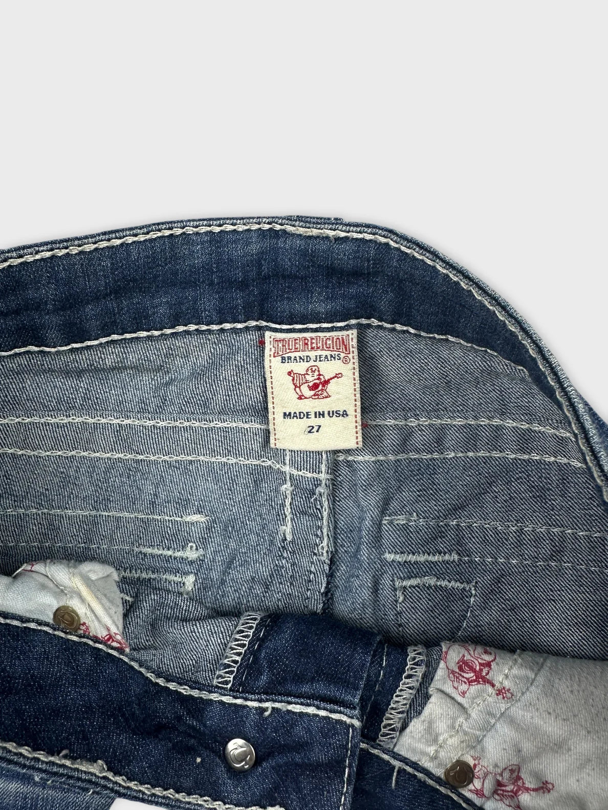 Back view of a denim skirt featuring a distressed design and branded label.