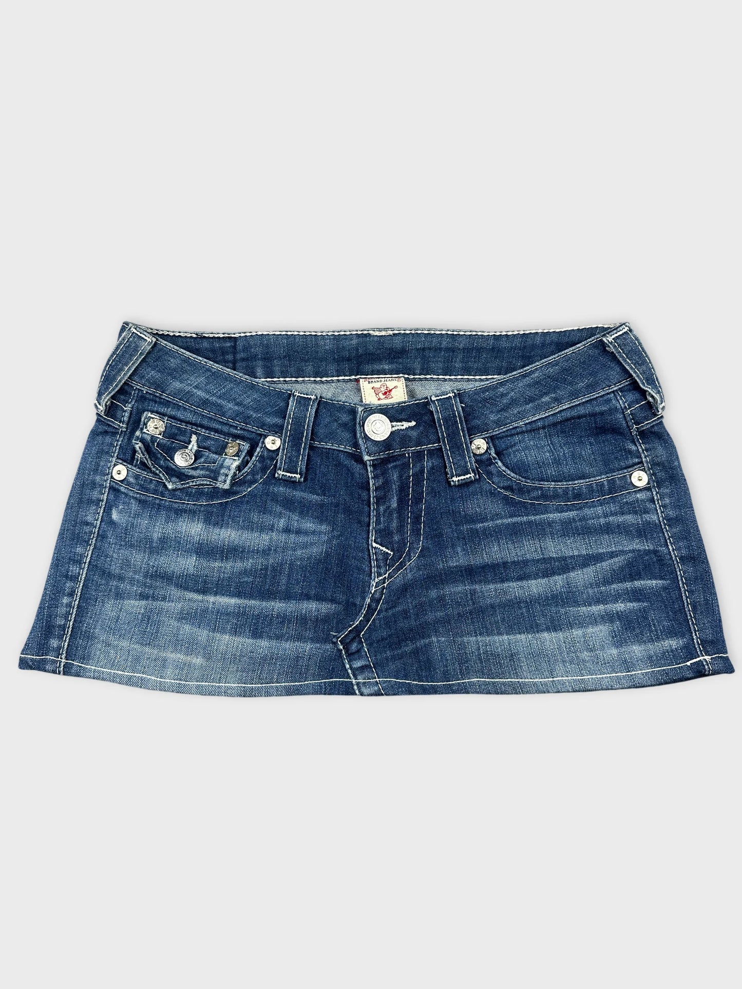 Front view of a denim skirt in dark blue with a silver button detail.