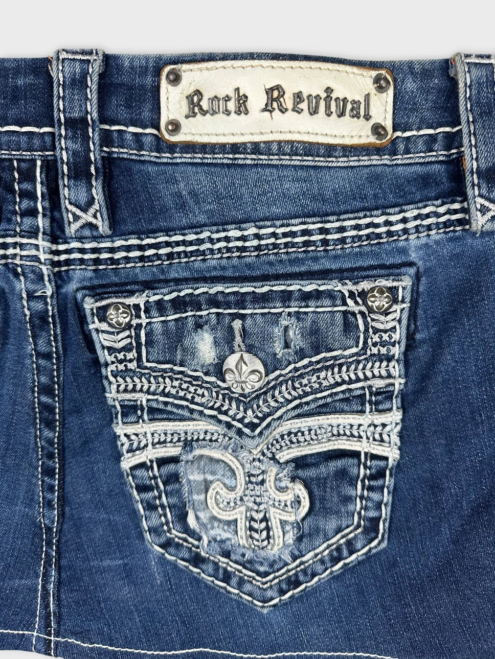 Detail view of a denim mini skirt in blue with decorative pocket stitching.
