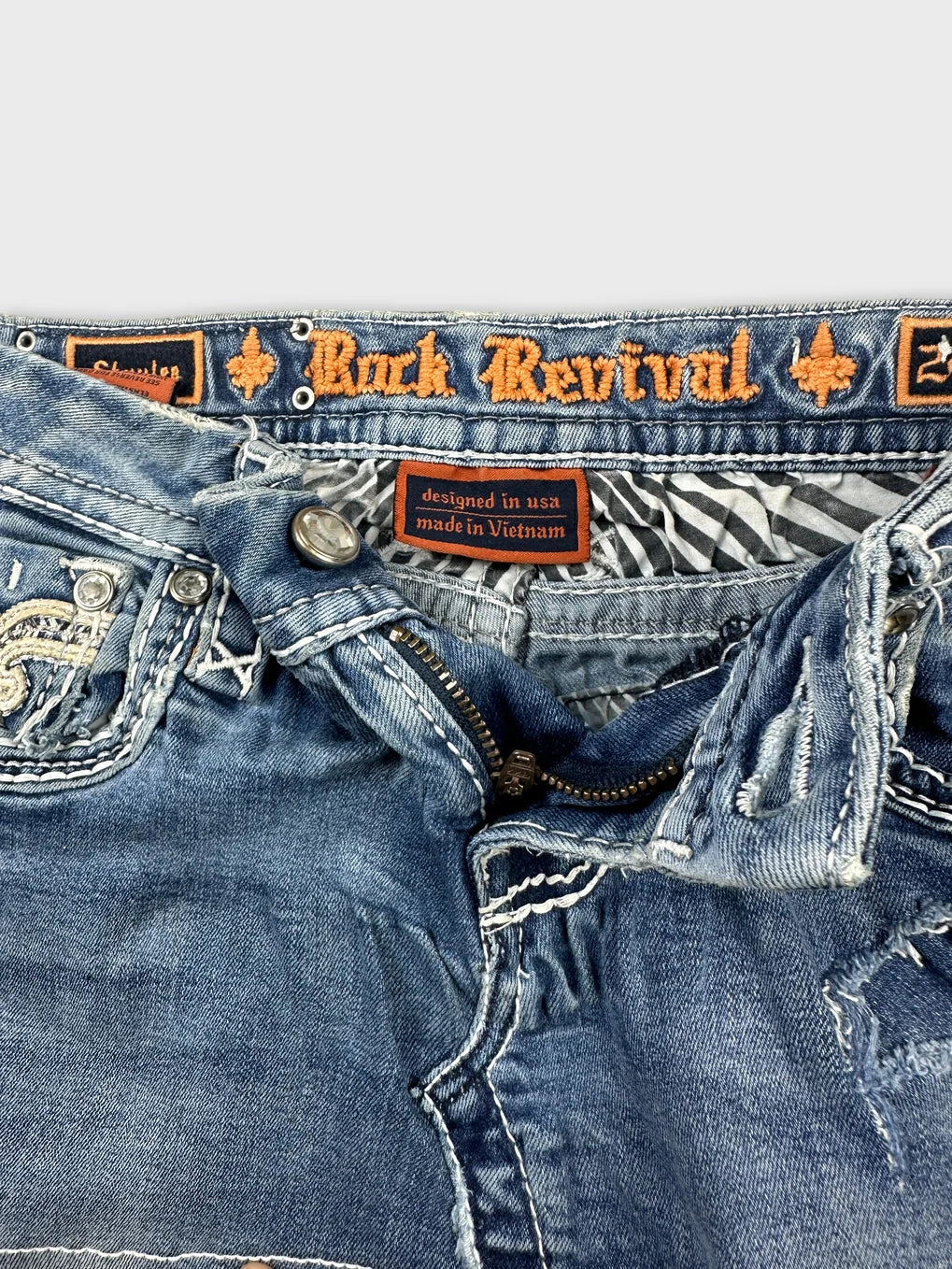 Detail view of a blue denim mini skirt with intricate stitching and a zipper.