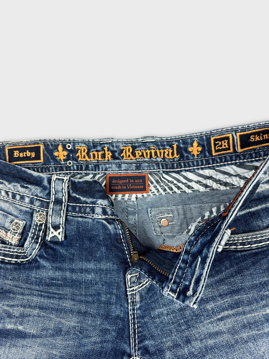 Detail view of denim shorts with a blue wash and embroidered brand label.
