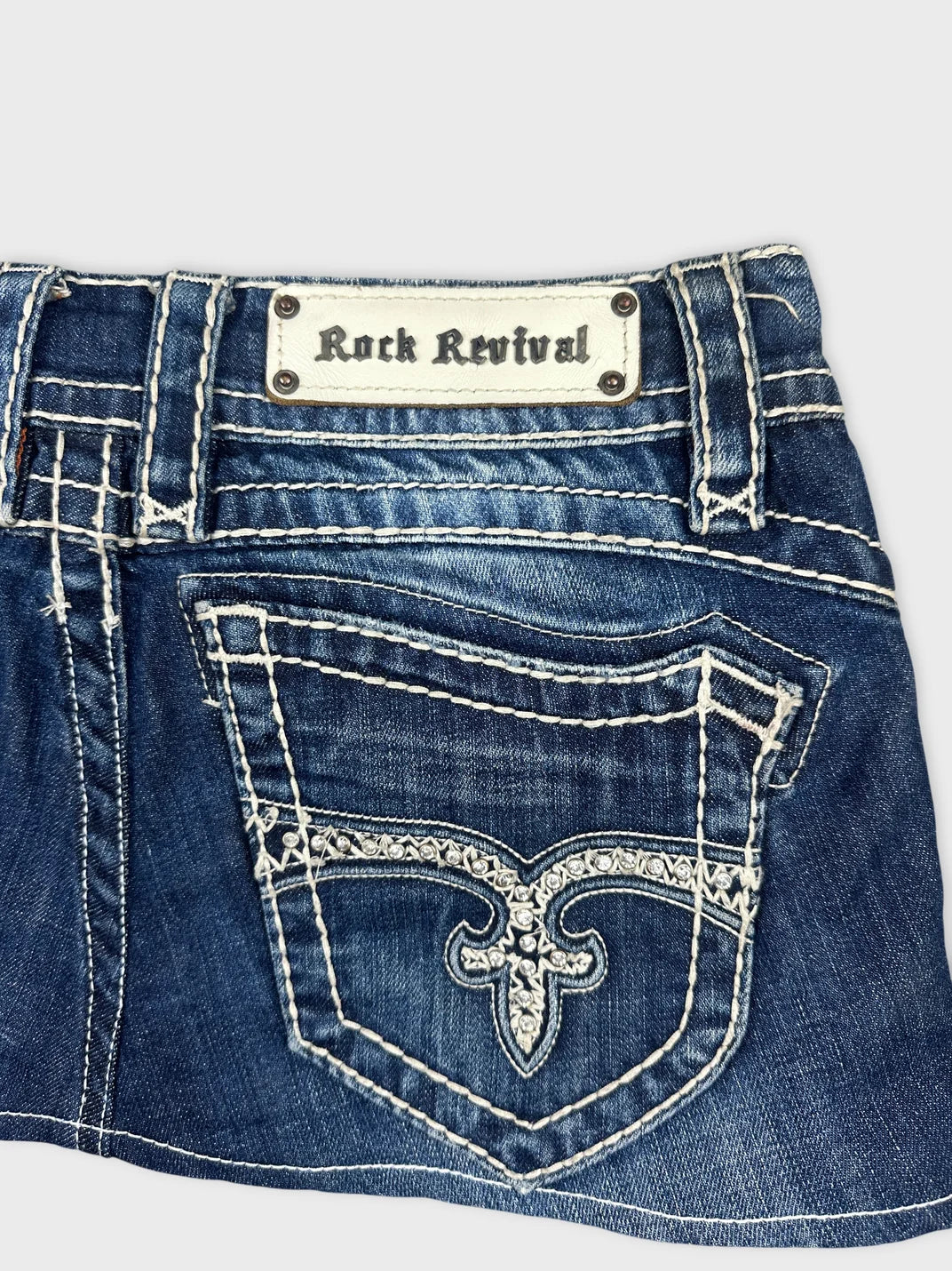 Detail view of women denim shorts in blue with decorative back pocket stitching.