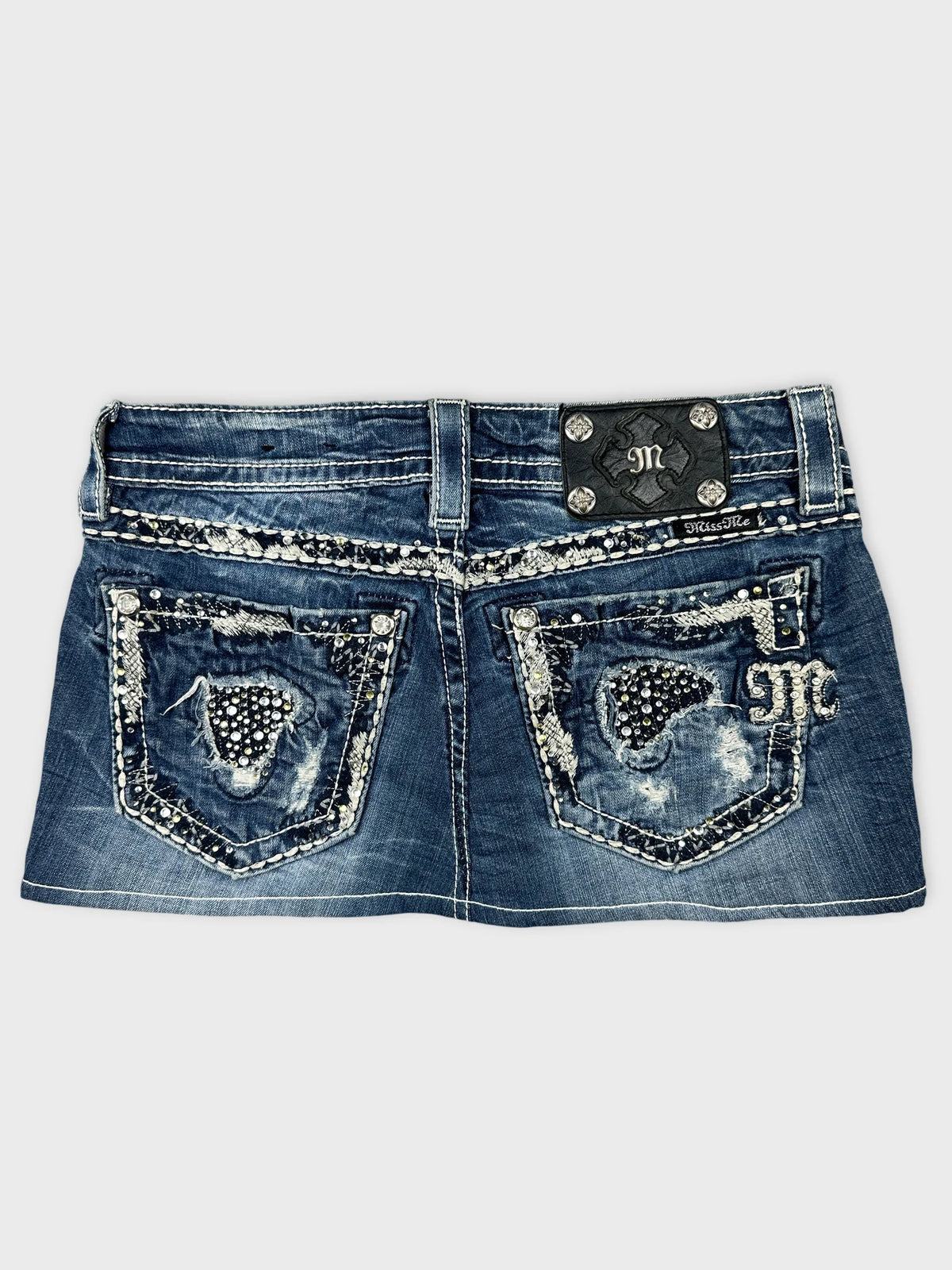 Back view of a denim skirt with embellished pockets in blue.
