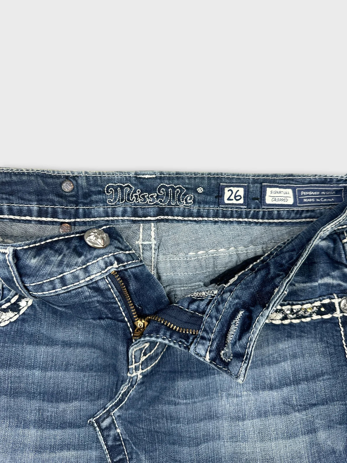 Detail view of a denim skirt featuring a visible zip and light blue color.