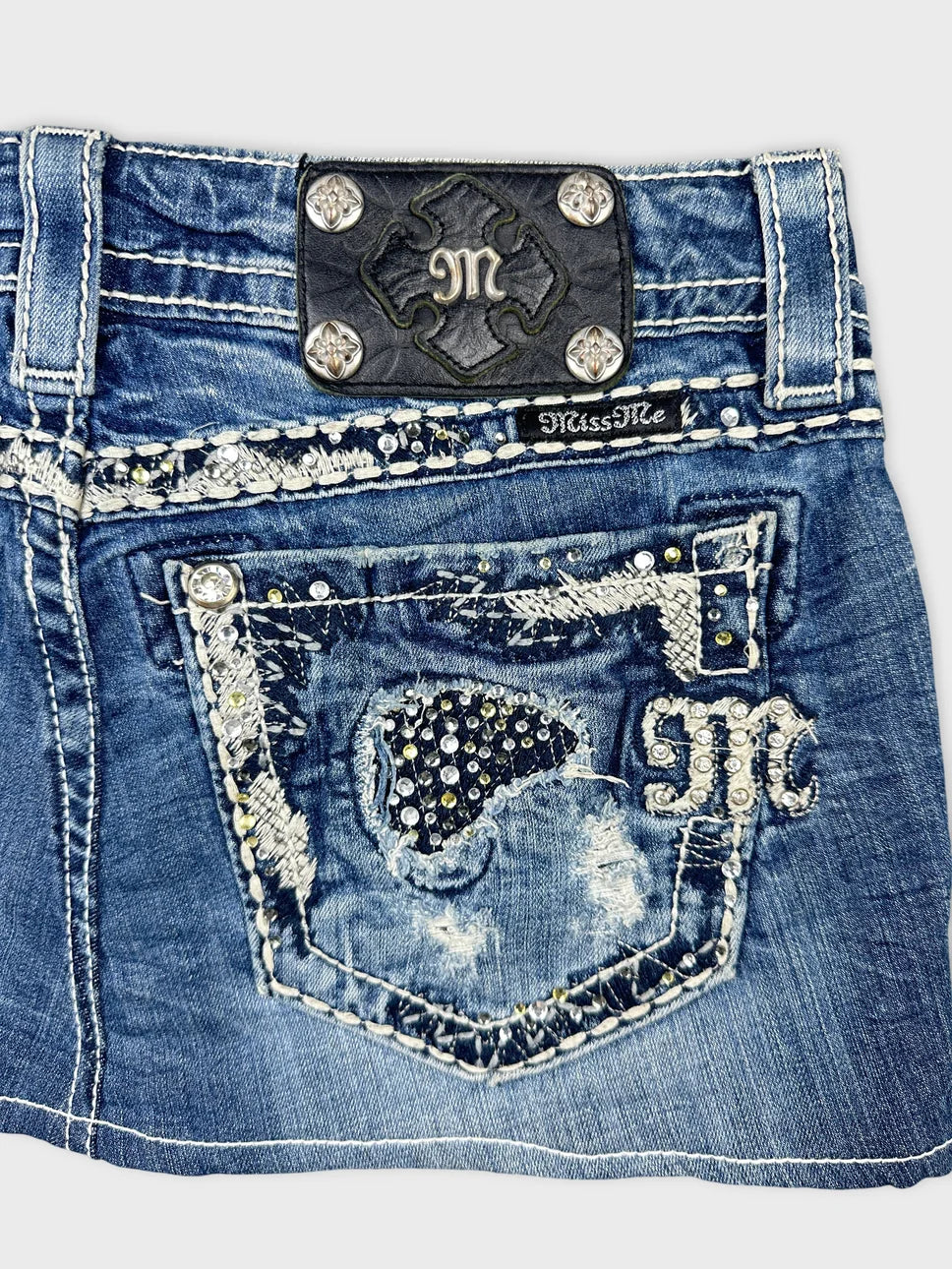 Detail view of a blue denim skirt featuring embellished back pockets.