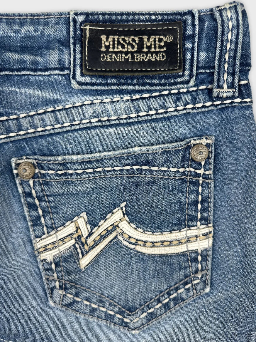 Detail view of blue denim skirt showing unique pocket embroidery design.