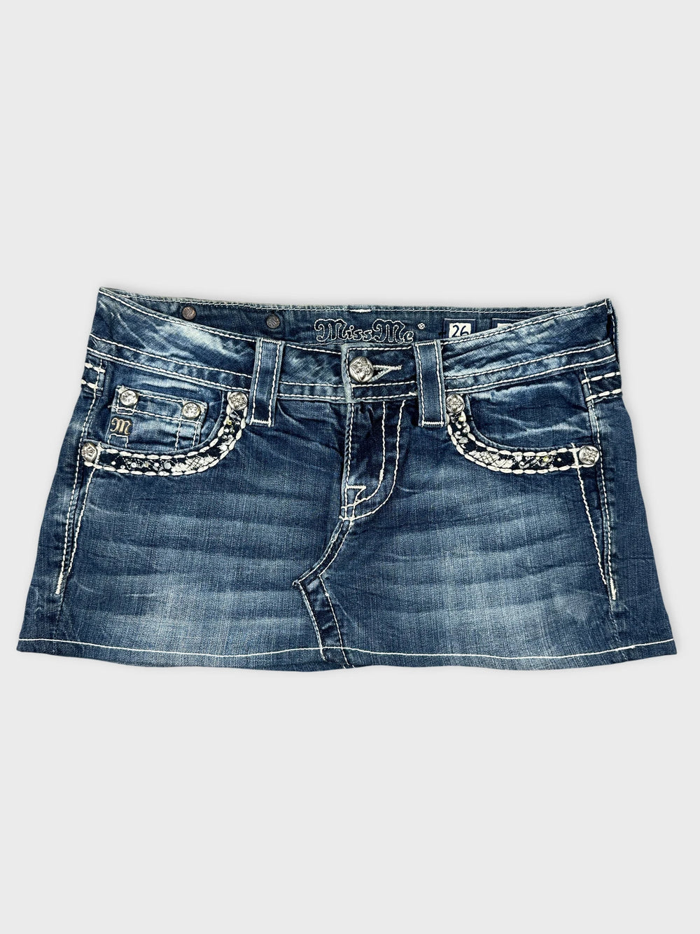Front view of a denim skirt with silver pocket embellishments.