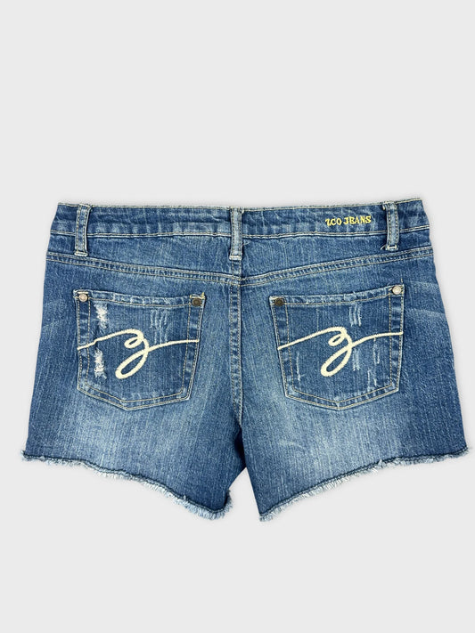 Back view of blue denim shorts featuring distressed details and embroidered pockets.