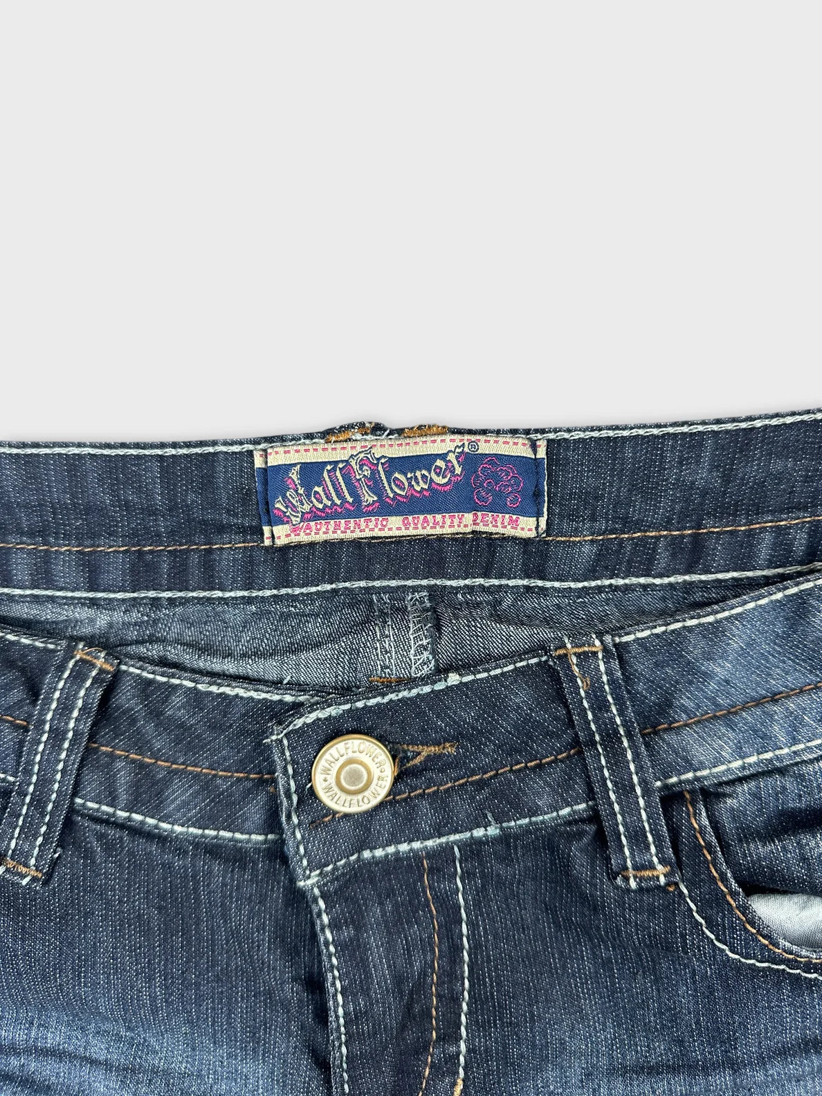 Detail view of navy blue women's denim shorts with embroidered brand tag.