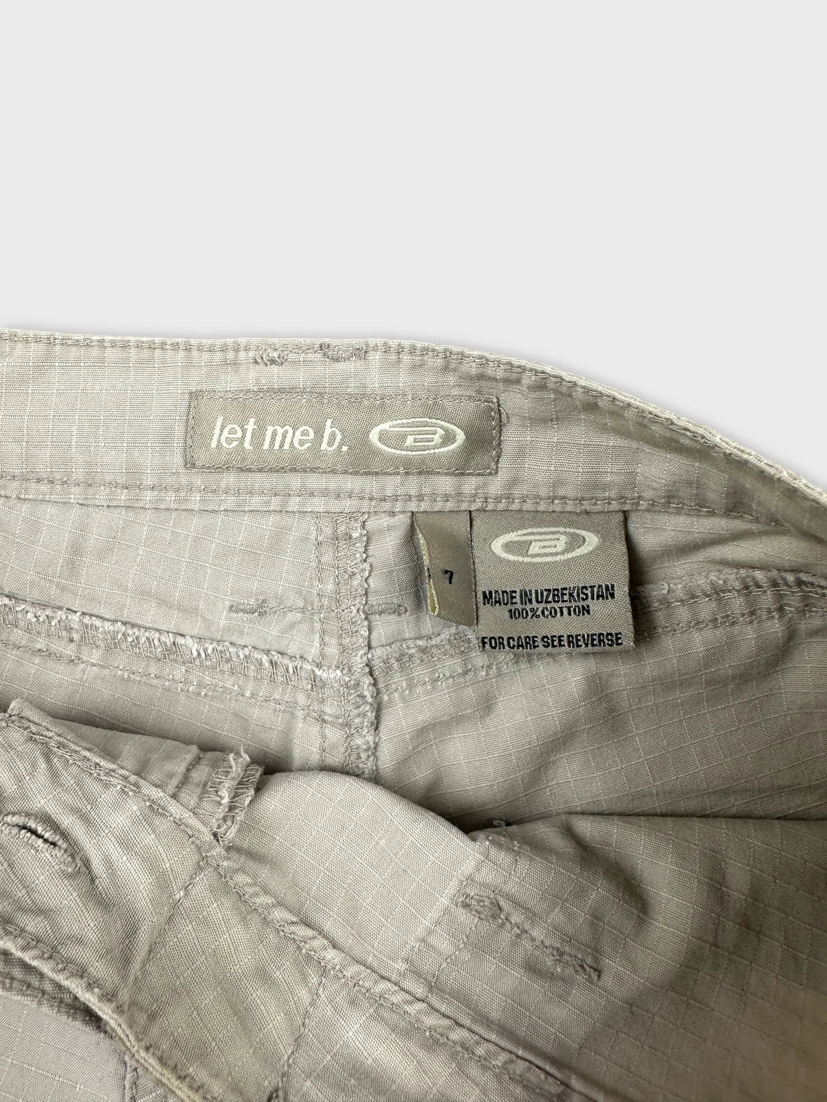 Detail view of gray women's denim shorts featuring a label and stitching.