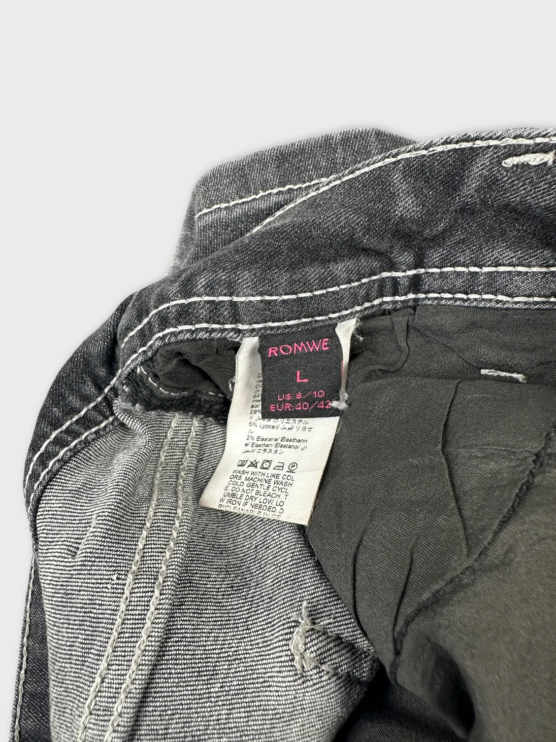 Detail view of black jeans shorts with white stitching and tag visible.