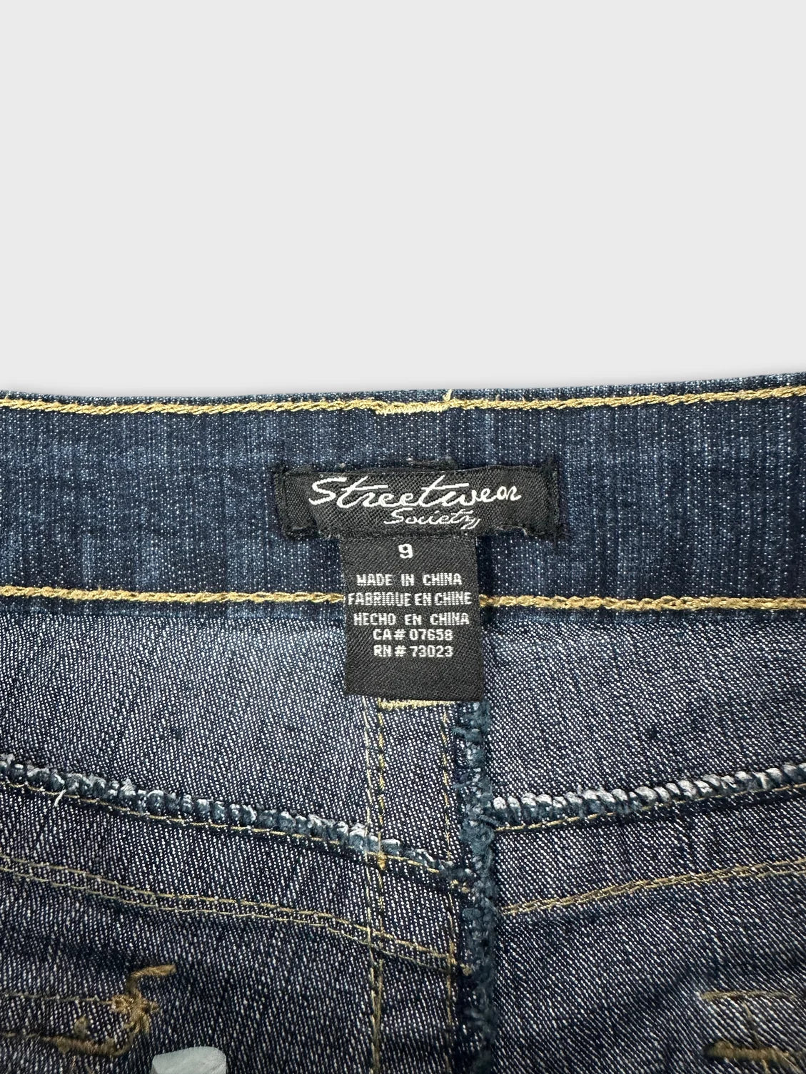 detail view of blue jeans shorts showing stitching and label