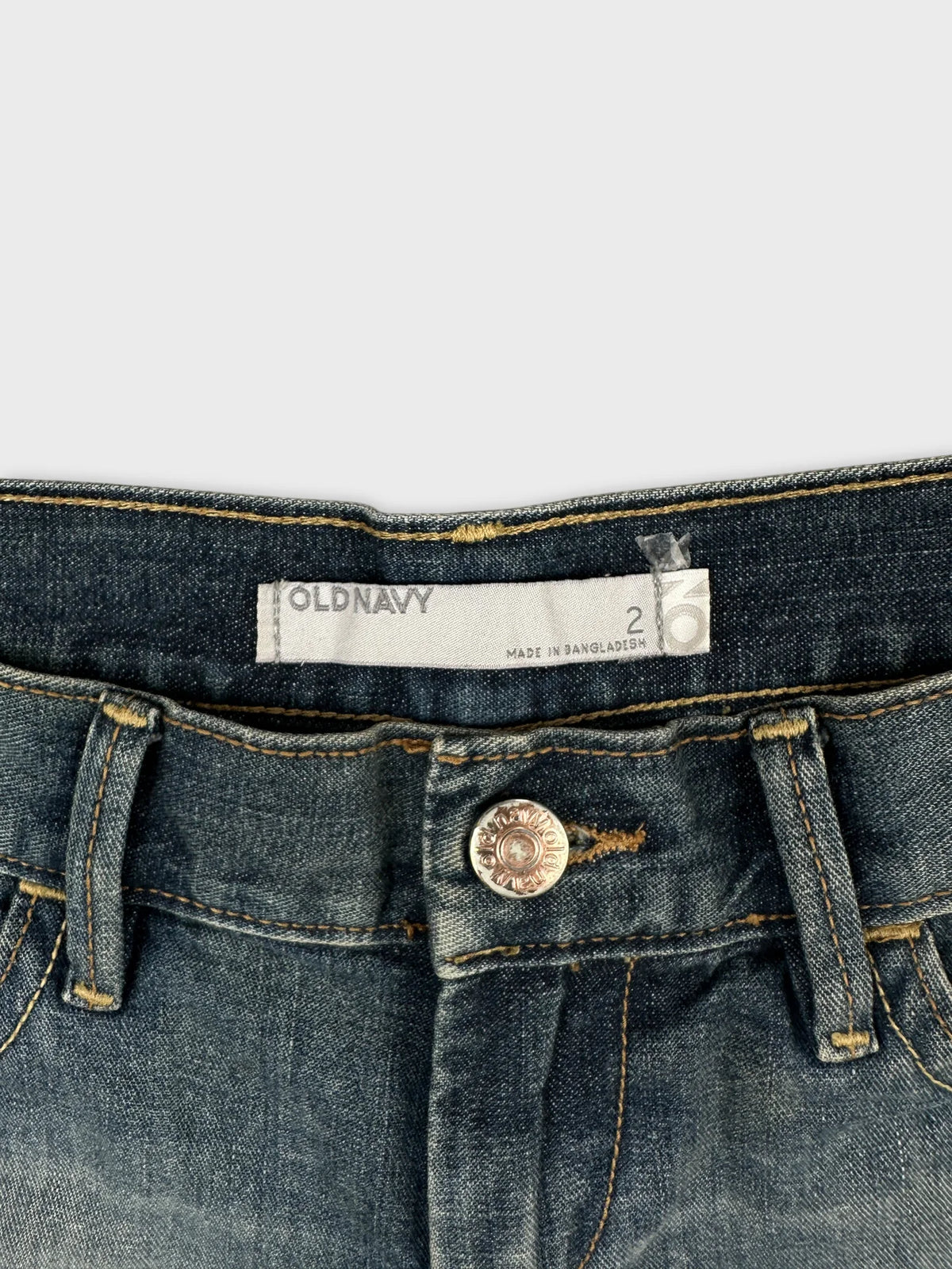 Detail view of dark blue jeans shorts with visible button and stitching.