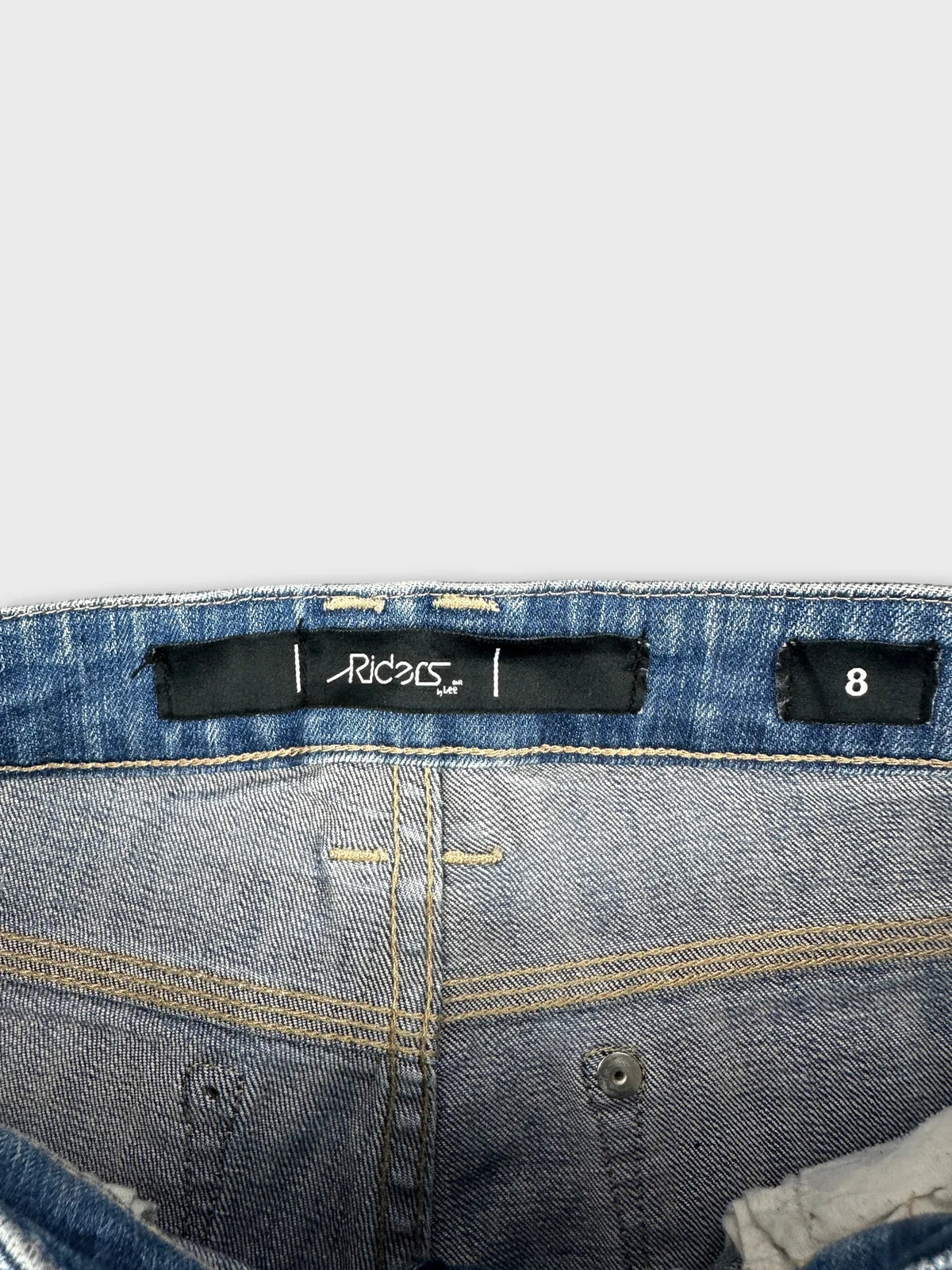 Detail view of blue jeans shorts with visible stitching and brand label.