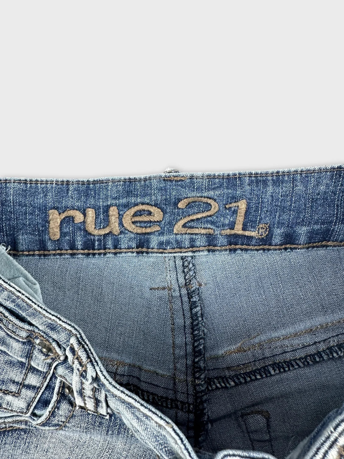 detail view of blue denim shorts featuring embroidered brand logo