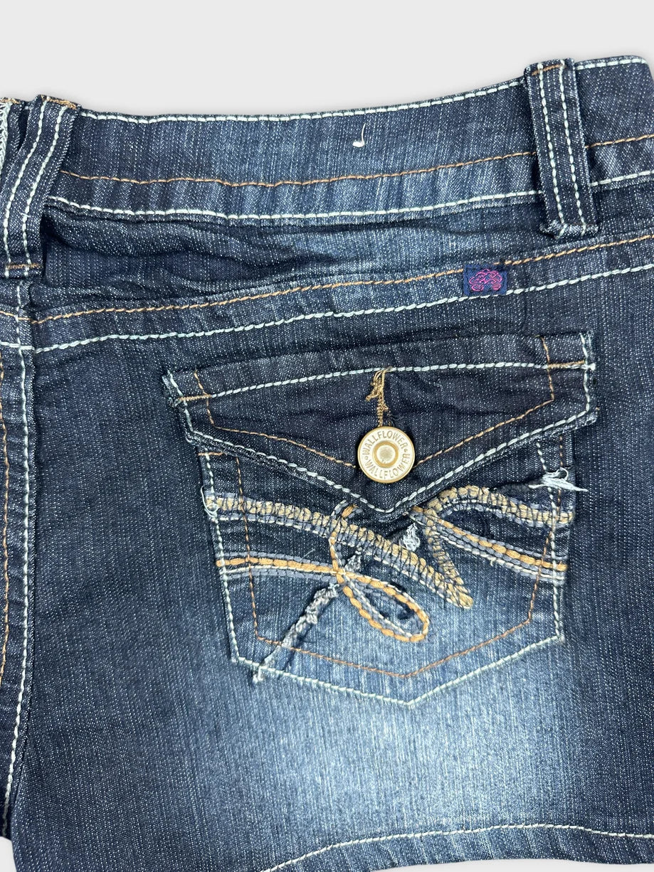 Detail view of dark denim shorts with stitched back pocket design.