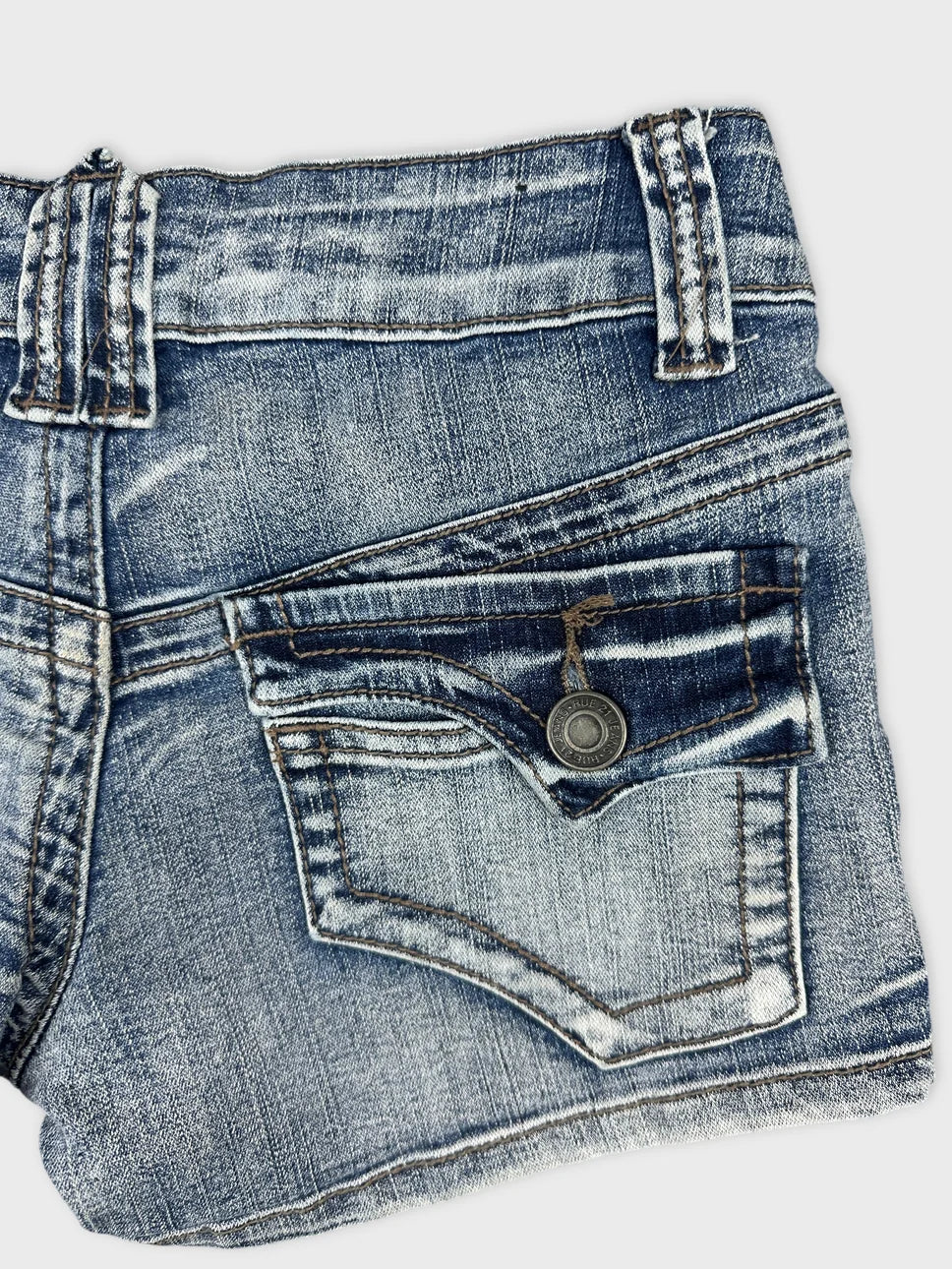 Detail view of denim shorts in blue with back pocket and stitching details