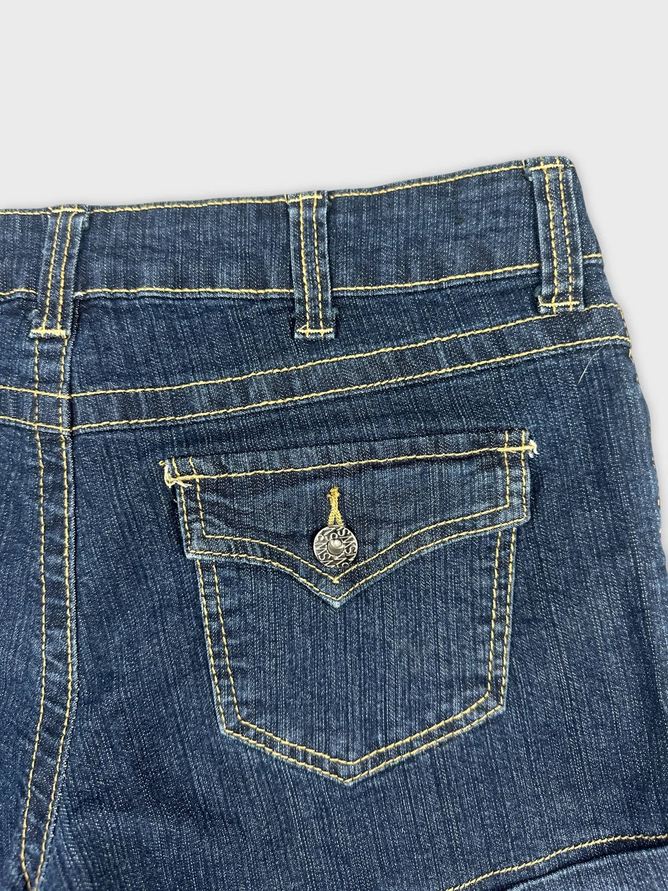 Detail view of dark blue denim shorts with yellow stitching and back pocket embellishments.