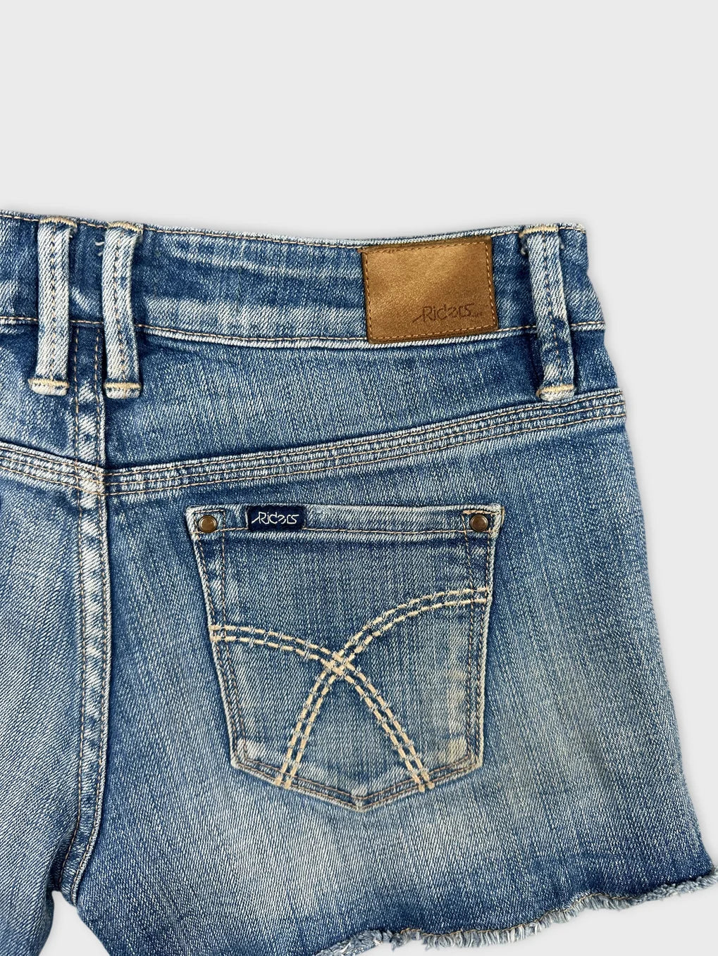 detail view of women's denim shorts in light blue with decorative stitching