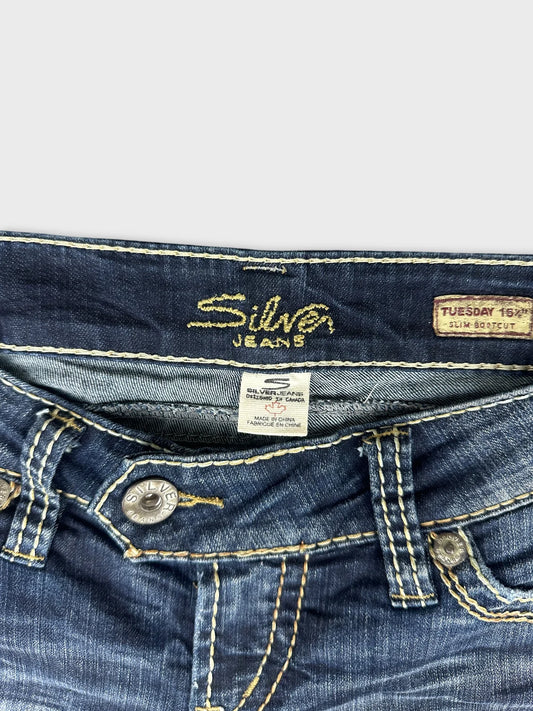 Back view of dark blue jeans featuring yellow stitching and button detail.