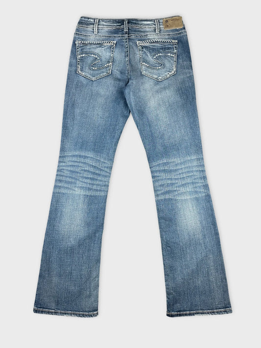 Back view of blue denim jeans featuring embroidered pockets.