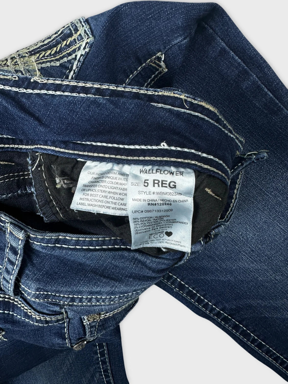 Detail view of blue jeans featuring decorative stitching and waistband details.