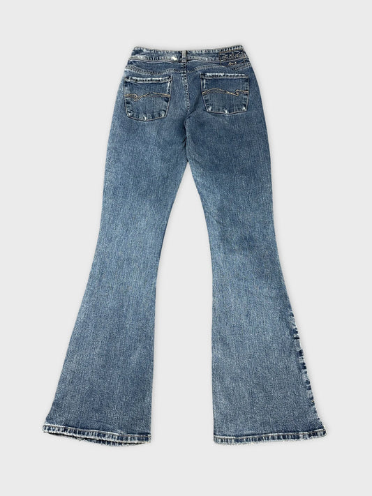 Back view of flared blue jeans with detailed stitching on pockets.
