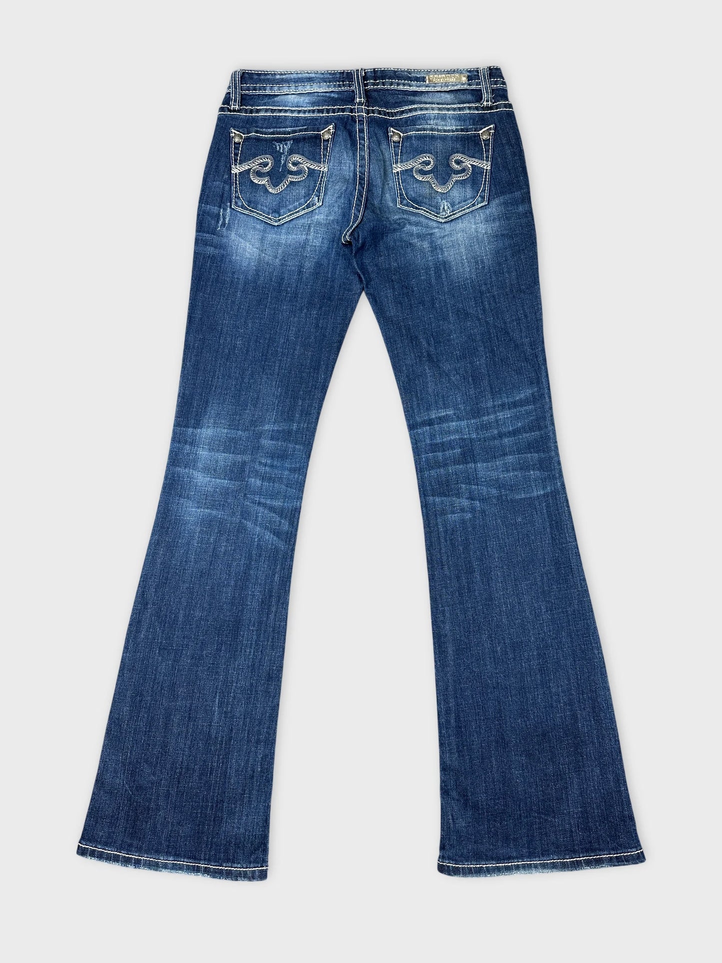 Back view of long blue jeans featuring decorative stitched pockets.